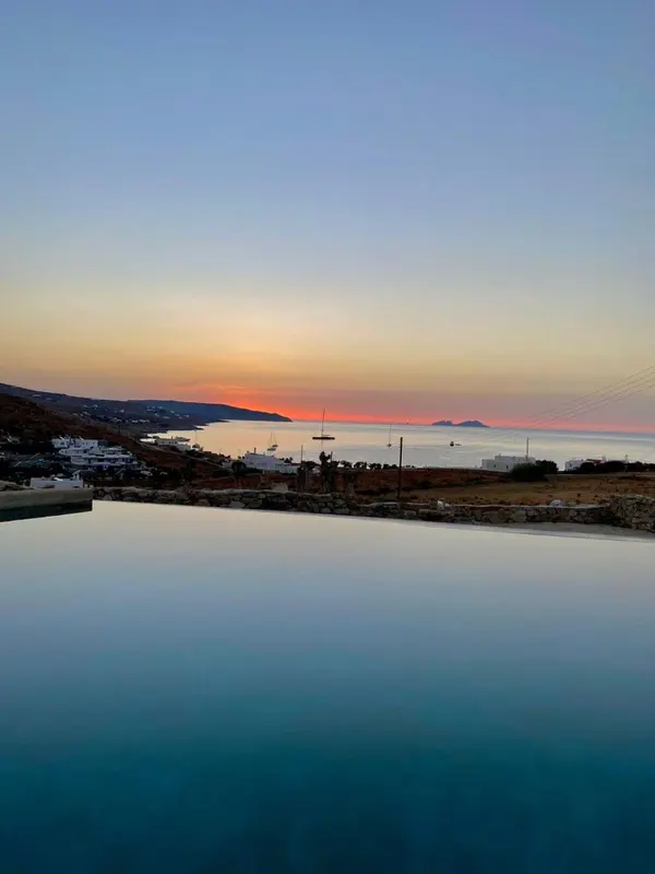 Vue d'une piscine à débordement sur la mer au coucher du soleil.