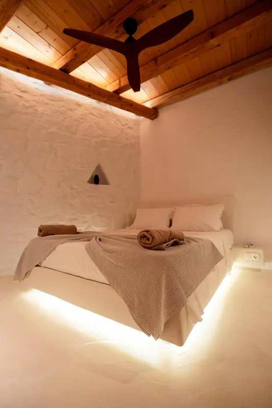 Une chambre lumineuse avec un lit blanc et un éclairage d'ambiance.