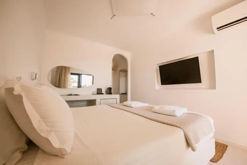 Une chambre lumineuse avec un grand lit et un téléviseur mural.