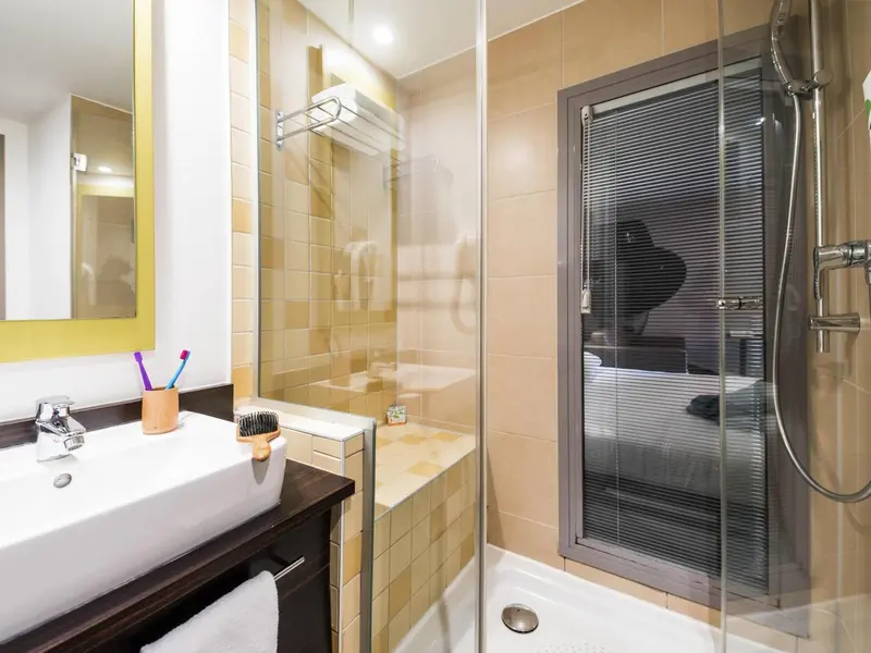 Une salle de bain avec douche vitrée et lavabo.