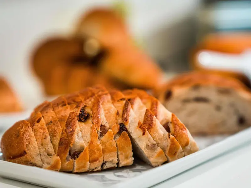 Pains et viennoiseries disposés sur un présentoir blanc.