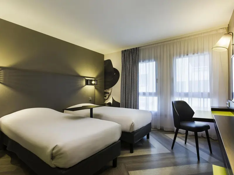 Une chambre d'hôtel moderne avec deux lits simples et un bureau.