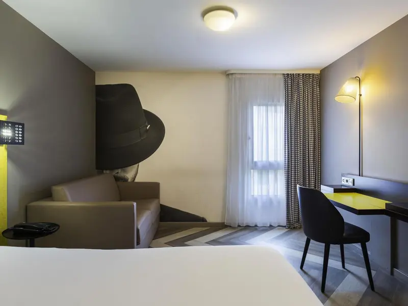 Une chambre lumineuse avec un canapé et un bureau près d'une fenêtre.