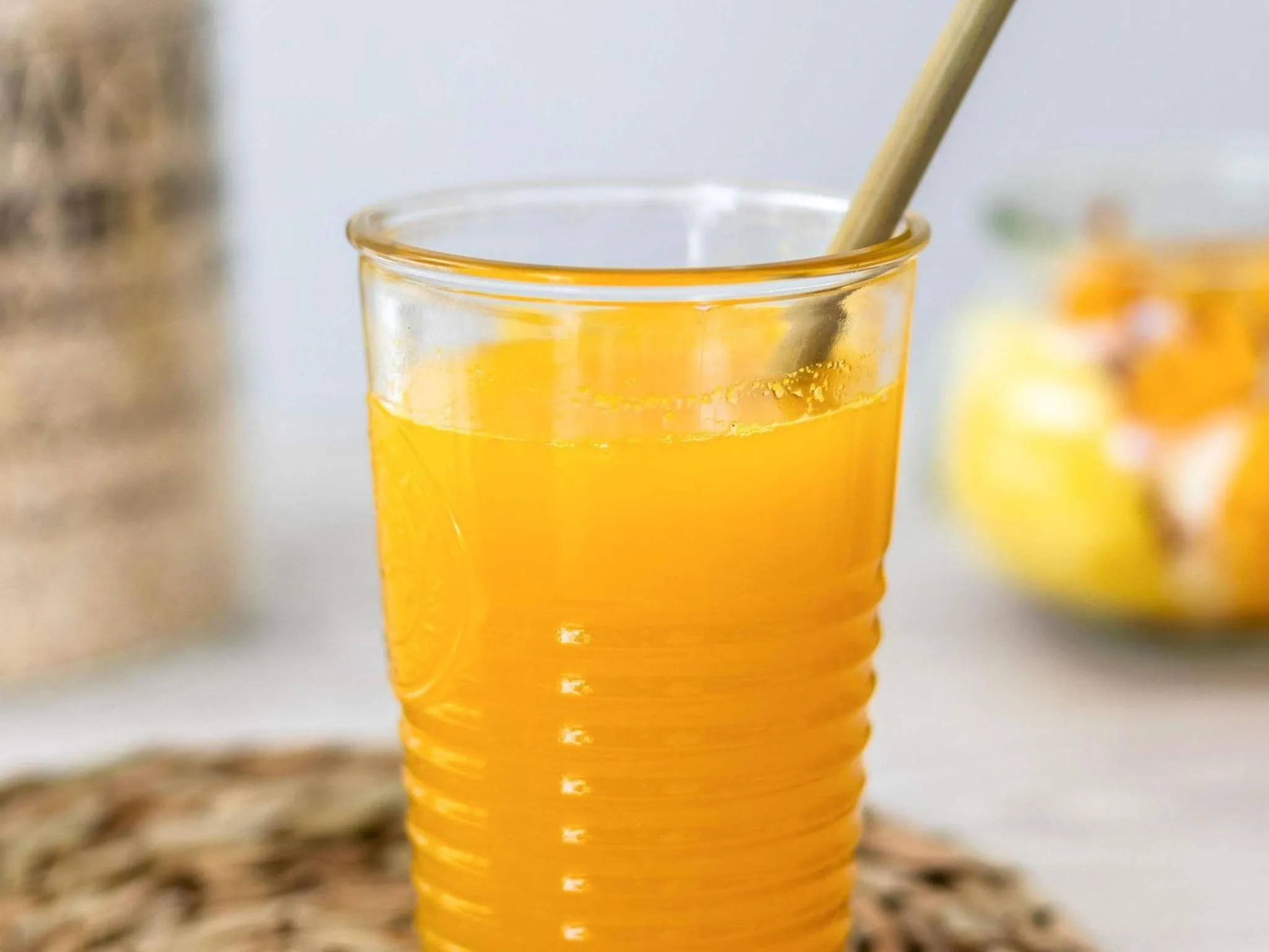Un verre de jus d'orange frais sur une table en rotin.