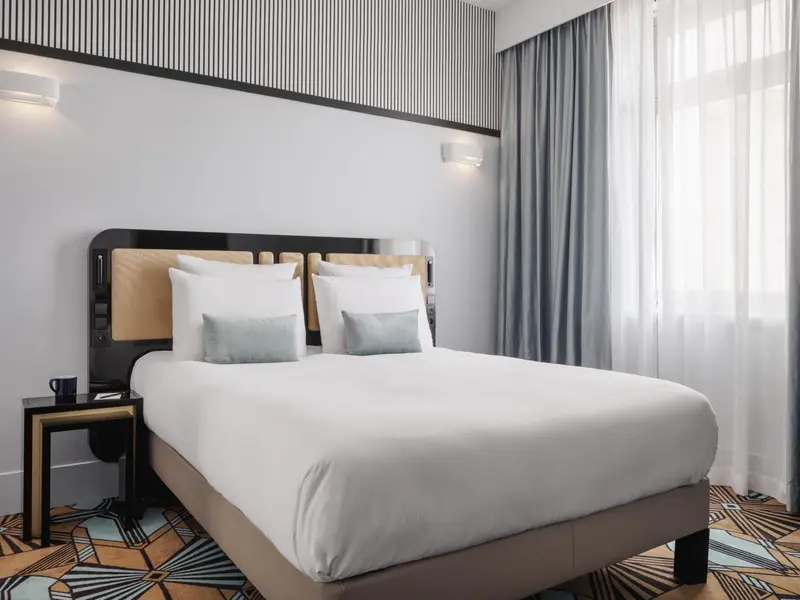 Une chambre lumineuse avec un grand lit recouvert de coussins.