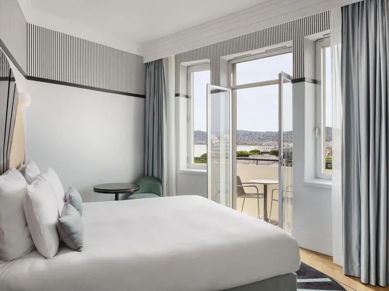 Une chambre lumineuse avec un grand lit et une vue sur la mer.