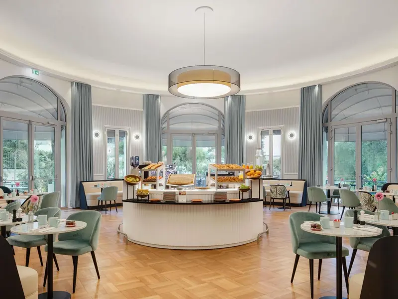 Une salle lumineuse avec un buffet de petit-déjeuner et des tables.