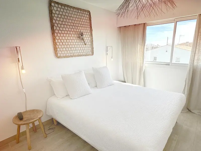 Une chambre lumineuse avec un grand lit recouvert d'une couette blanche et des oreillers.