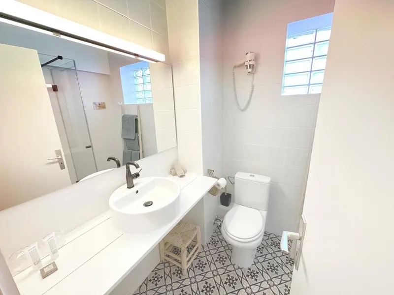 Une salle de bain claire avec douche à l'italienne et carrelage décoratif.