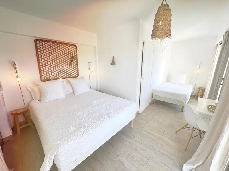 Chambre lumineuse avec un grand lit et un lit simple.