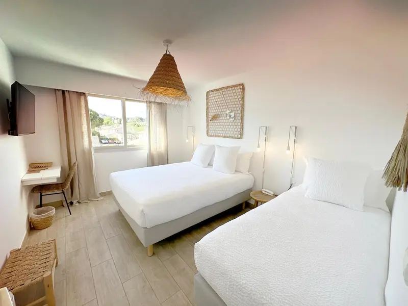 Une chambre lumineuse avec deux lits simples et un lit double.