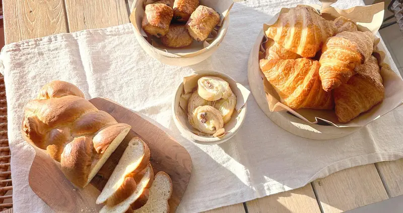 Assortiment de viennoiseries et de pains frais sur une table en bois.