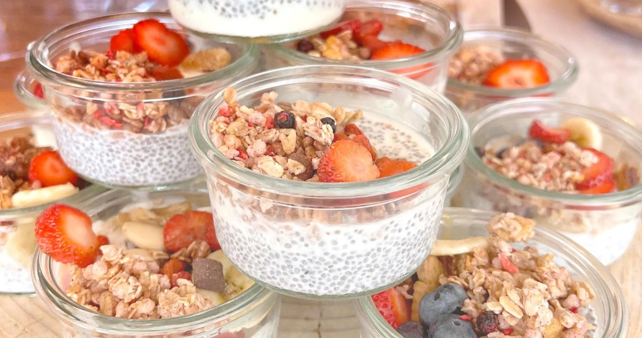 Des coupes de yaourt aux fruits et granola sont présentées sur une table.