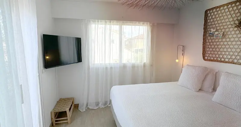 Une chambre lumineuse avec un lit et une télévision murale.