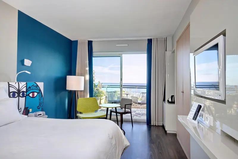Une chambre lumineuse avec un lit blanc et une vue sur la mer.