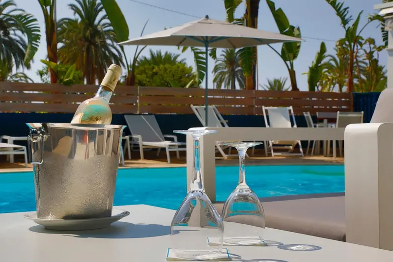 Une bouteille de champagne dans un seau à glace près d'une piscine avec des transats.