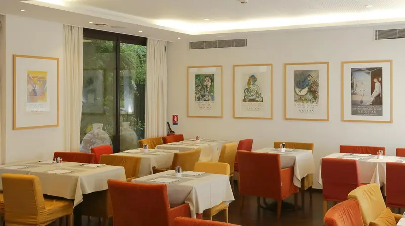 Une salle lumineuse avec des tables dressées pour un repas.