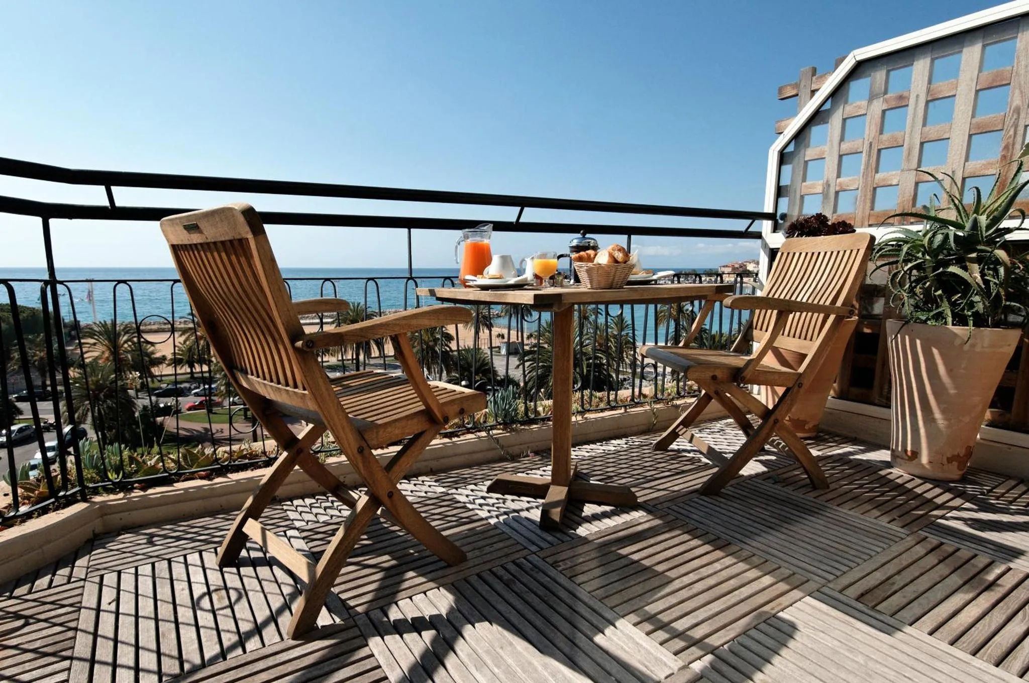 Une table de petit-déjeuner est dressée sur une terrasse avec vue sur la mer.