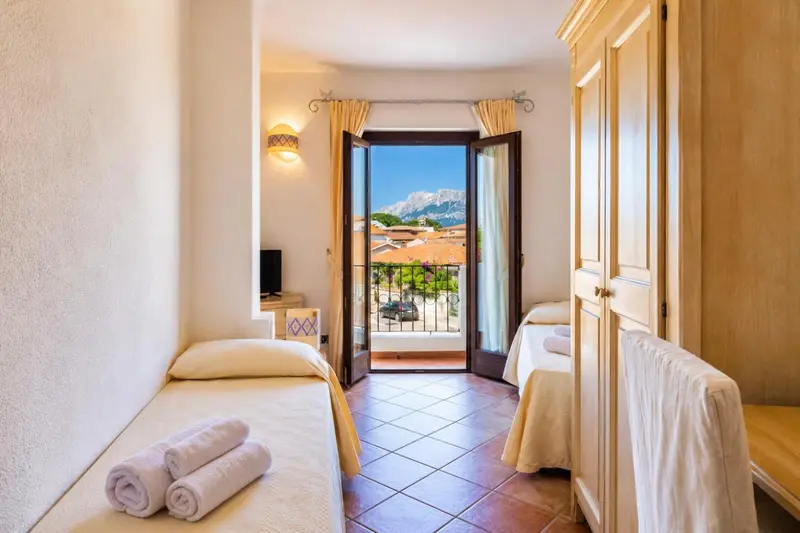 Une chambre lumineuse avec deux lits simples et une vue sur un paysage montagneux.