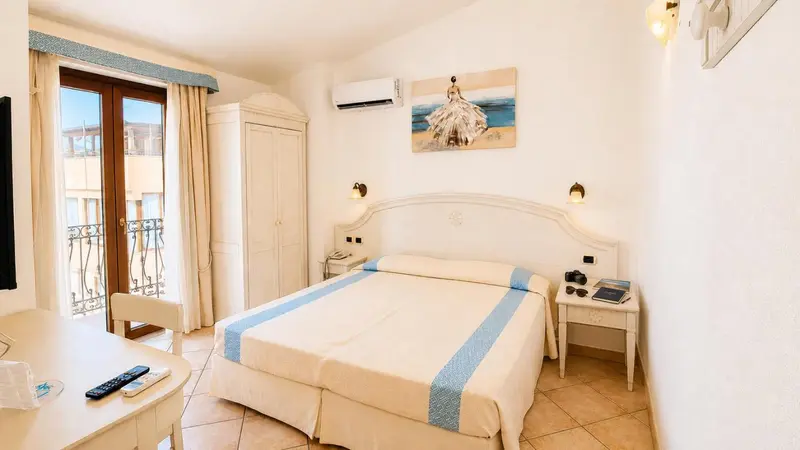 Une chambre lumineuse avec un lit double et un accès à un balcon.