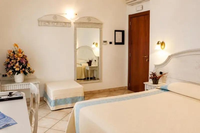 Une chambre lumineuse avec un lit double et un miroir décoratif.