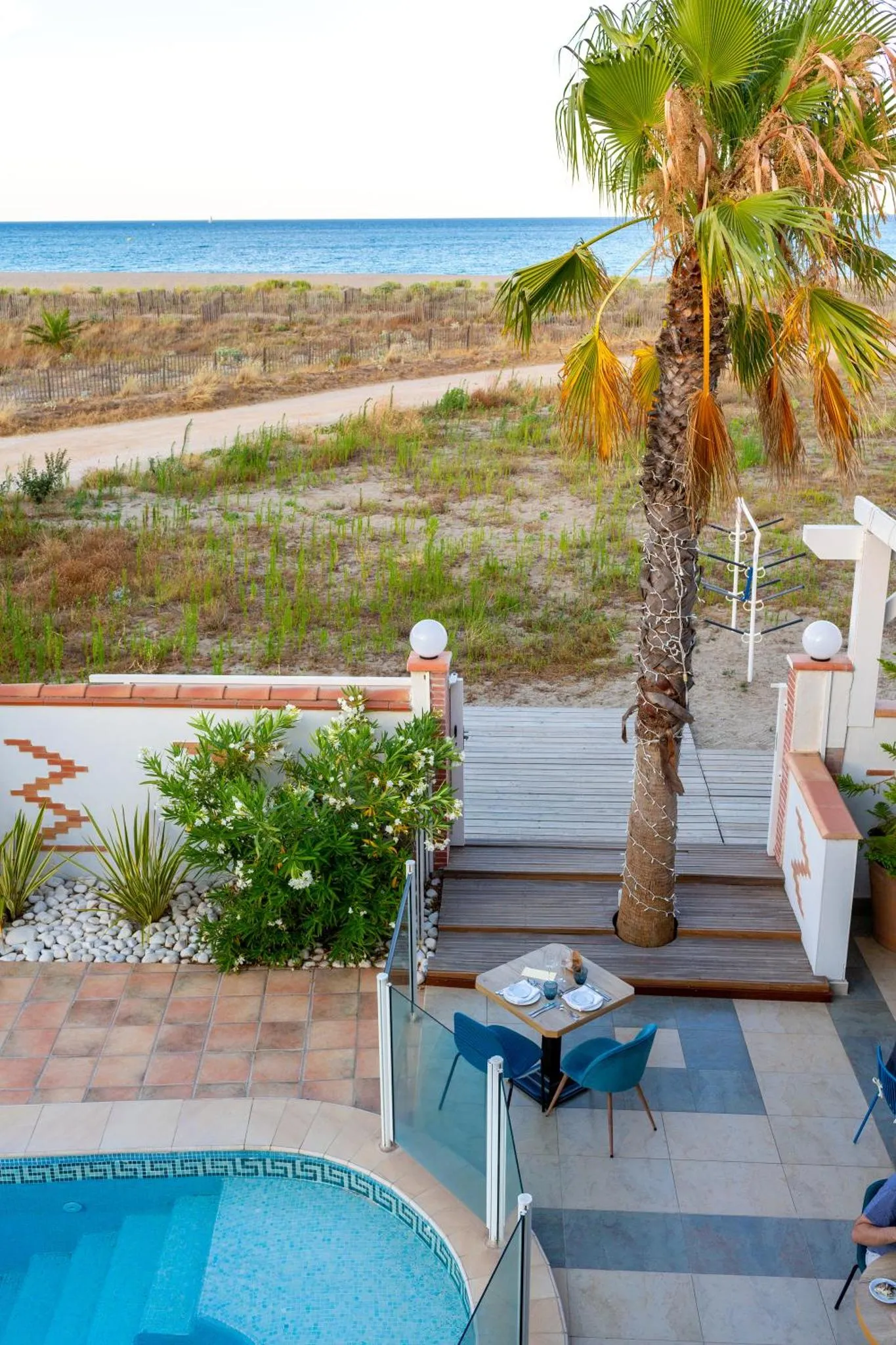 Terrasse avec table et chaises près d'une piscine et vue sur la mer.
