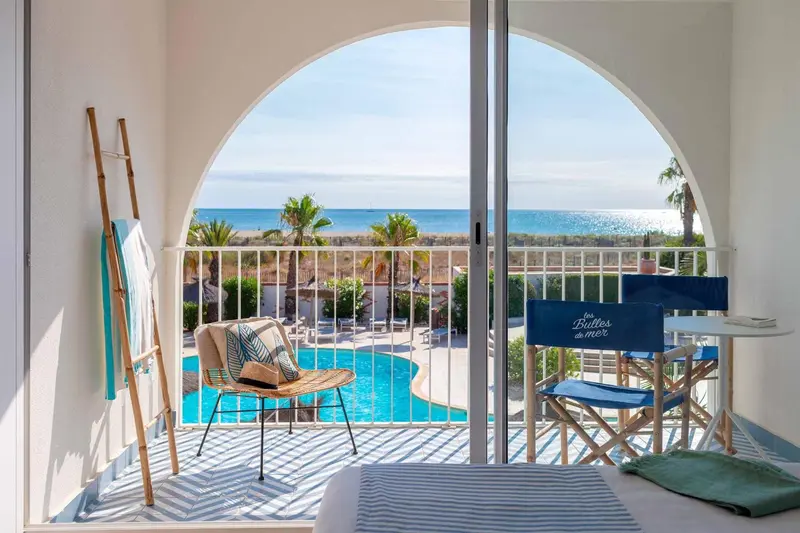 Vue sur la mer depuis une terrasse ensoleillée avec mobilier de jardin.