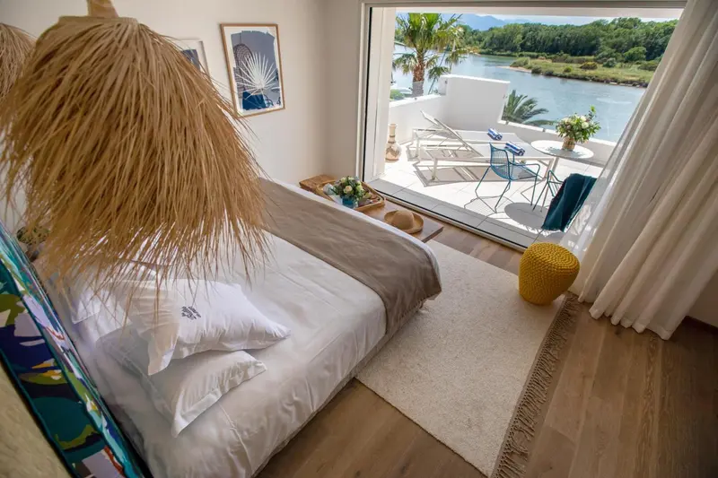 Une chambre lumineuse s'ouvre sur une terrasse avec vue sur l'eau.