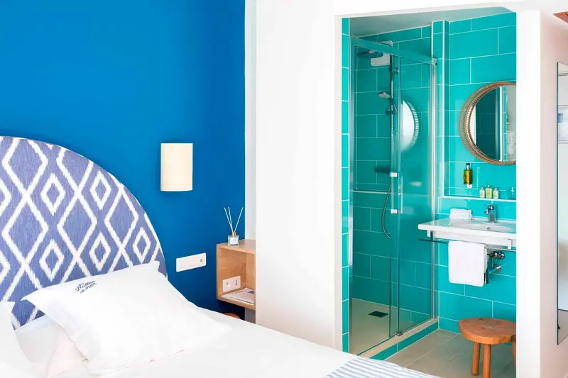 Chambre moderne avec un mur bleu vif et une salle de bain carrelée de turquoise.