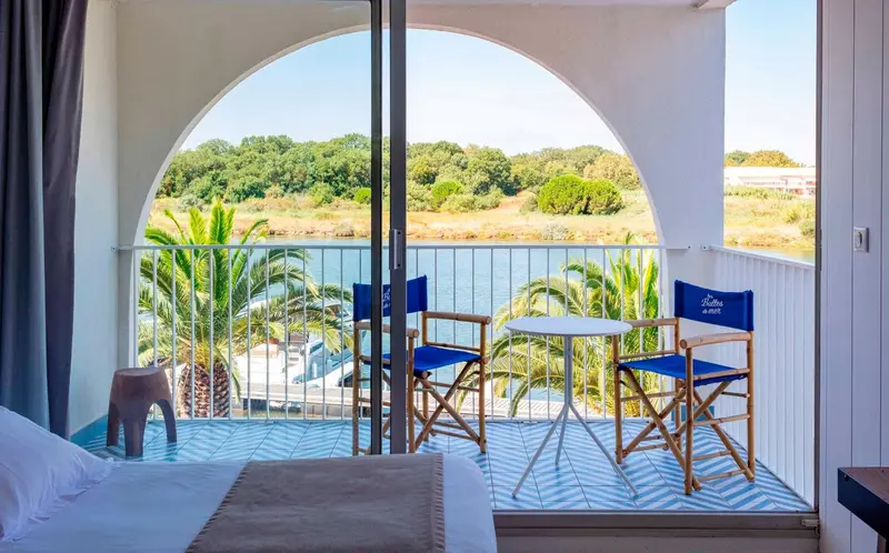 Une terrasse ensoleillée offre une vue sur la végétation et l'eau.