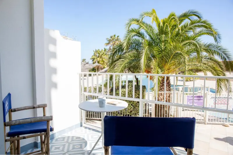 Une terrasse avec une table et des chaises offre une vue sur la végétation et la mer.