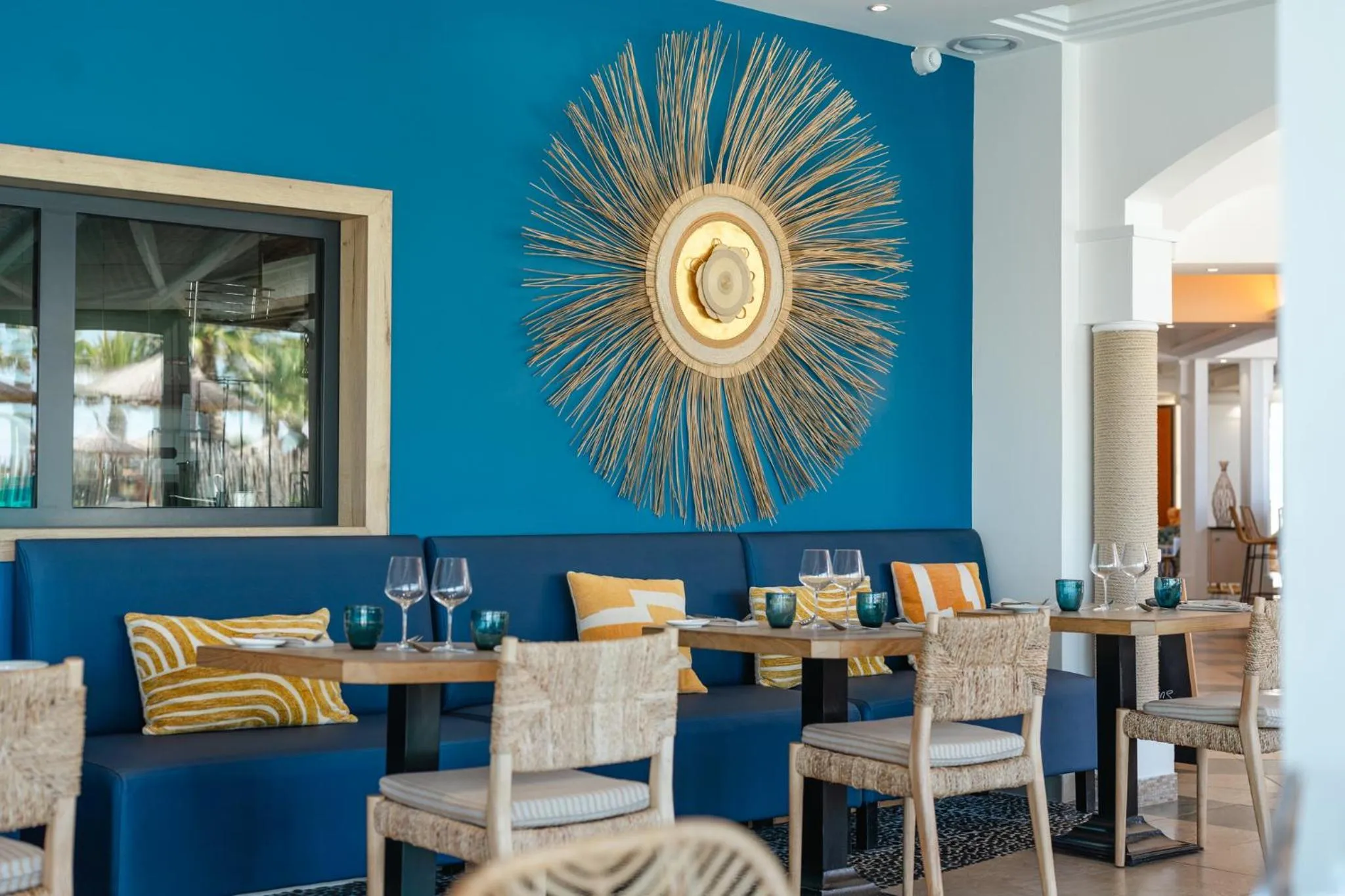 Une salle à manger lumineuse avec des tables dressées et des banquettes bleues.