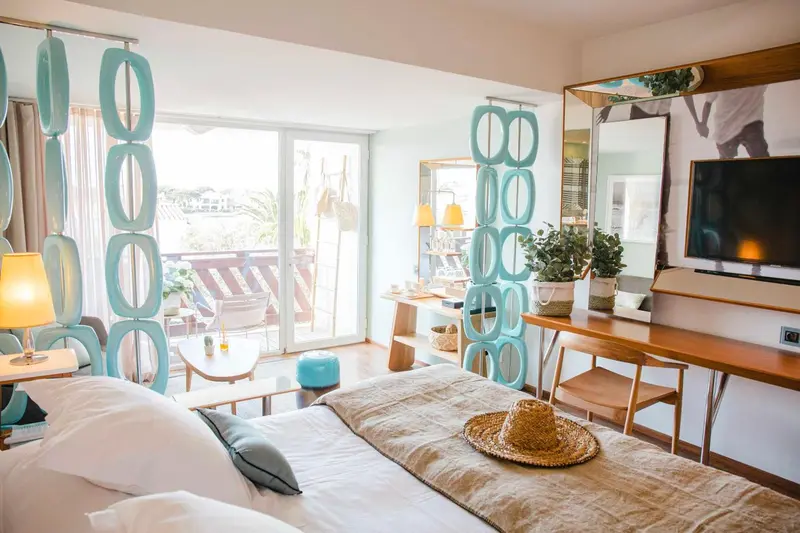 Chambre lumineuse avec un grand lit et un accès à une terrasse ensoleillée.