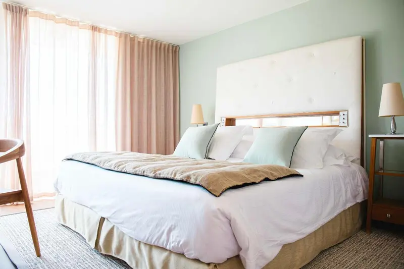 Une chambre lumineuse avec un grand lit et des oreillers décoratifs.