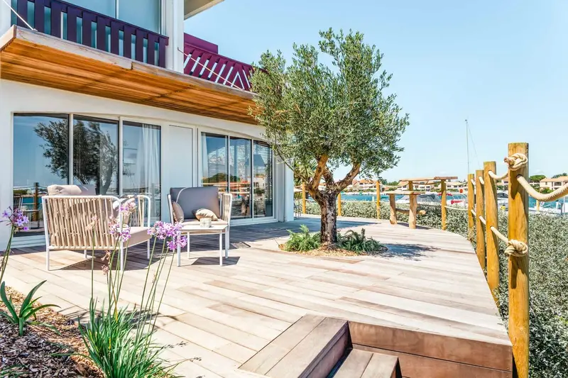 Terrasse en bois avec mobilier d'extérieur et végétation luxuriante.
