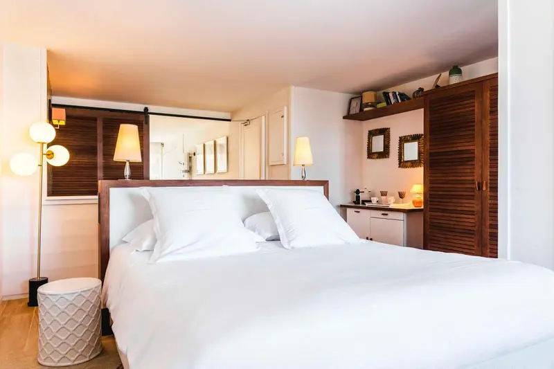 Une chambre lumineuse avec un grand lit recouvert de draps blancs.