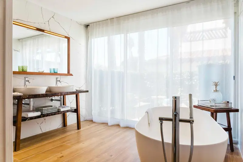 Une salle de bain lumineuse avec une baignoire et un double vasque.