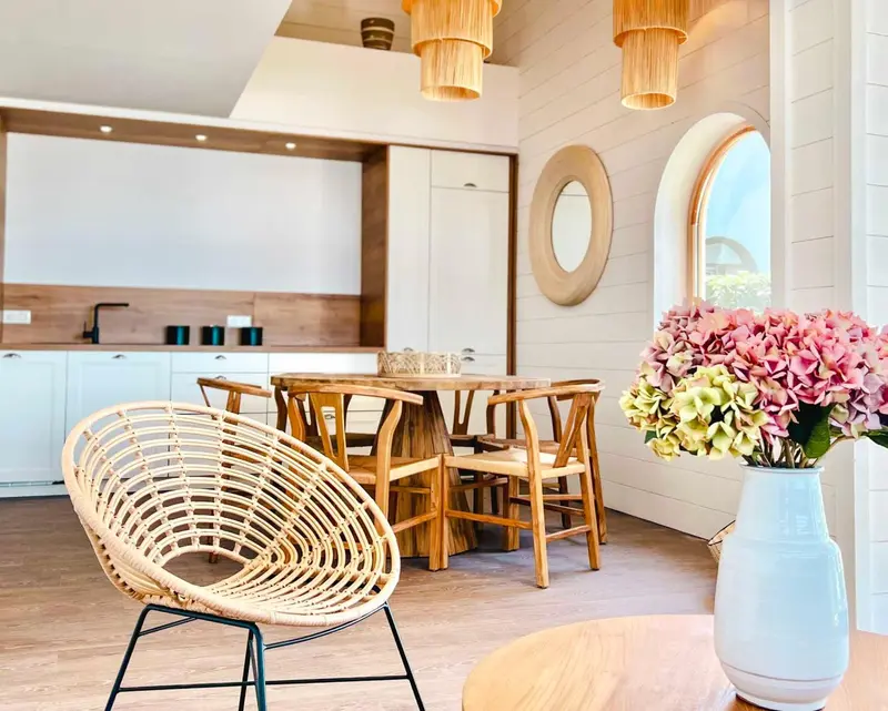Une salle à manger lumineuse avec une table en bois et des chaises en osier.