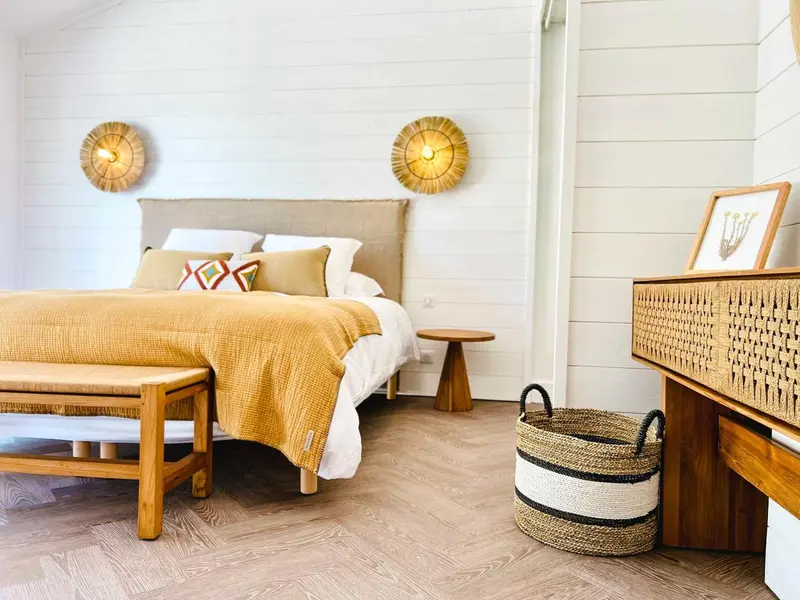 Une chambre lumineuse avec un grand lit recouvert d'une couverture jaune et de coussins décoratifs.