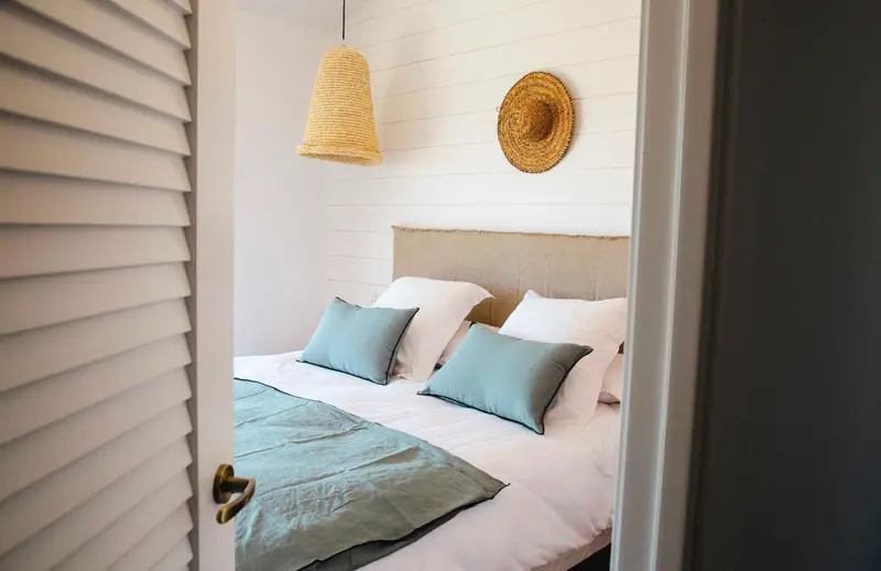 Une chambre lumineuse avec un lit double et des oreillers verts.