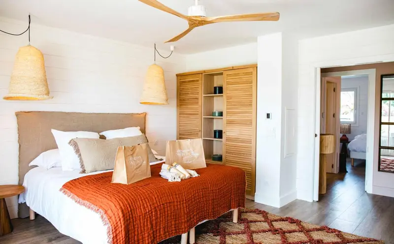 Une chambre à coucher lumineuse avec un lit recouvert d'une couverture orange et de coussins.
