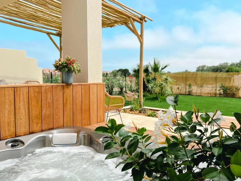 Un espace extérieur aménagé avec un jacuzzi et une végétation luxuriante.