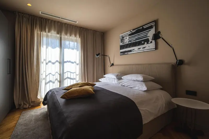 Une chambre avec un grand lit recouvert d'une couverture sombre et de coussins.