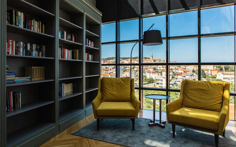 Un salon confortable avec deux fauteuils et une bibliothèque offre une vue sur la ville.