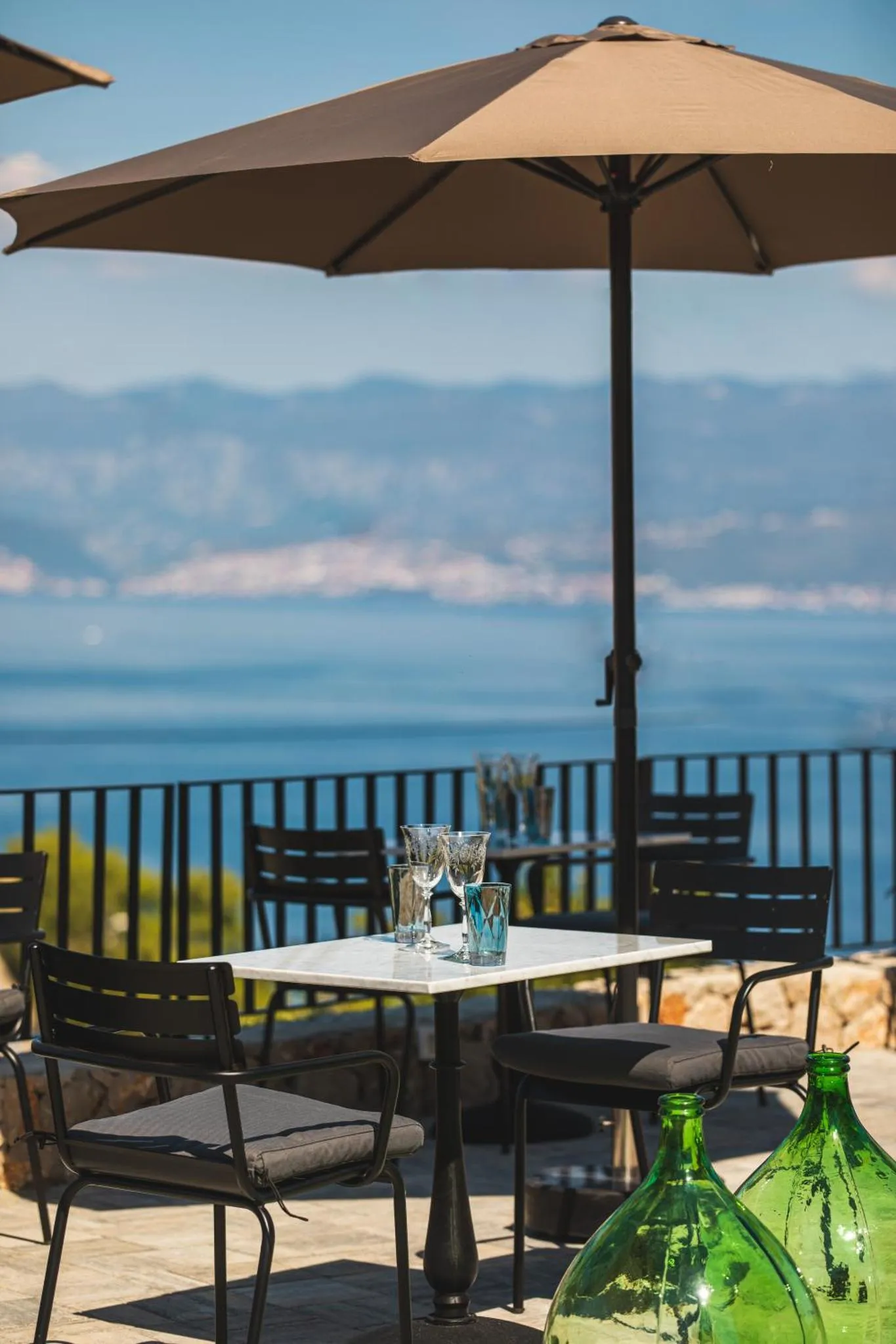 Terrasse avec tables et chaises donnant sur la mer.