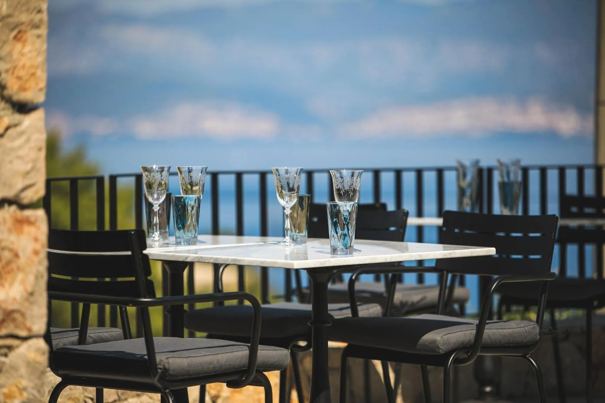 Une table est dressée sur une terrasse avec vue sur la mer.