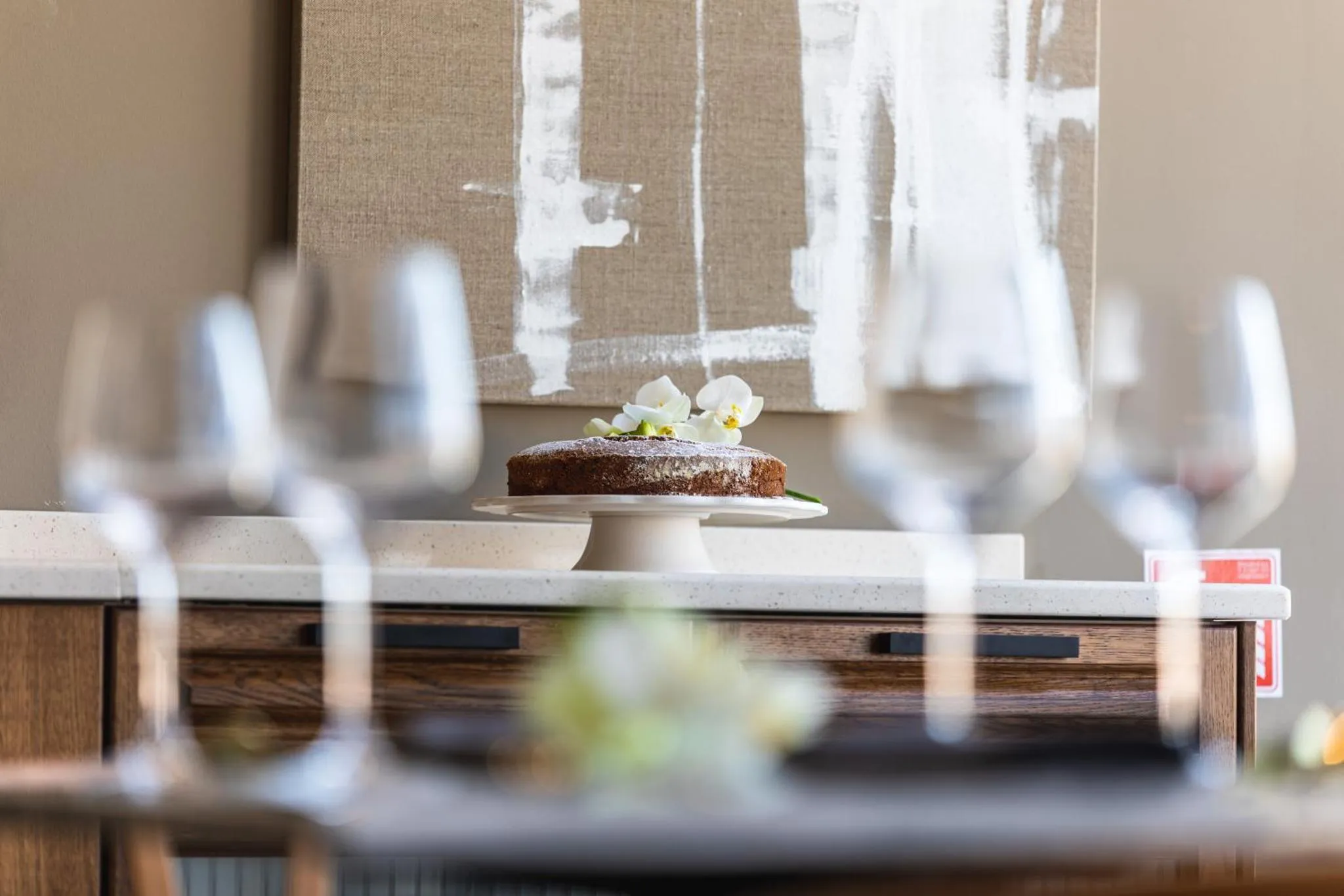 Une part de gâteau au chocolat est présentée sur une assiette, décorée d'une fleur blanche.