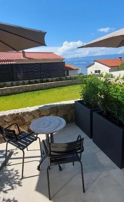 Terrasse avec mobilier de jardin et vue sur un paysage verdoyant.