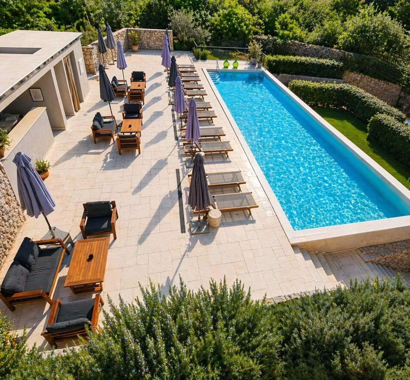 Terrasse avec transats et piscine rectangulaire en contrebas.