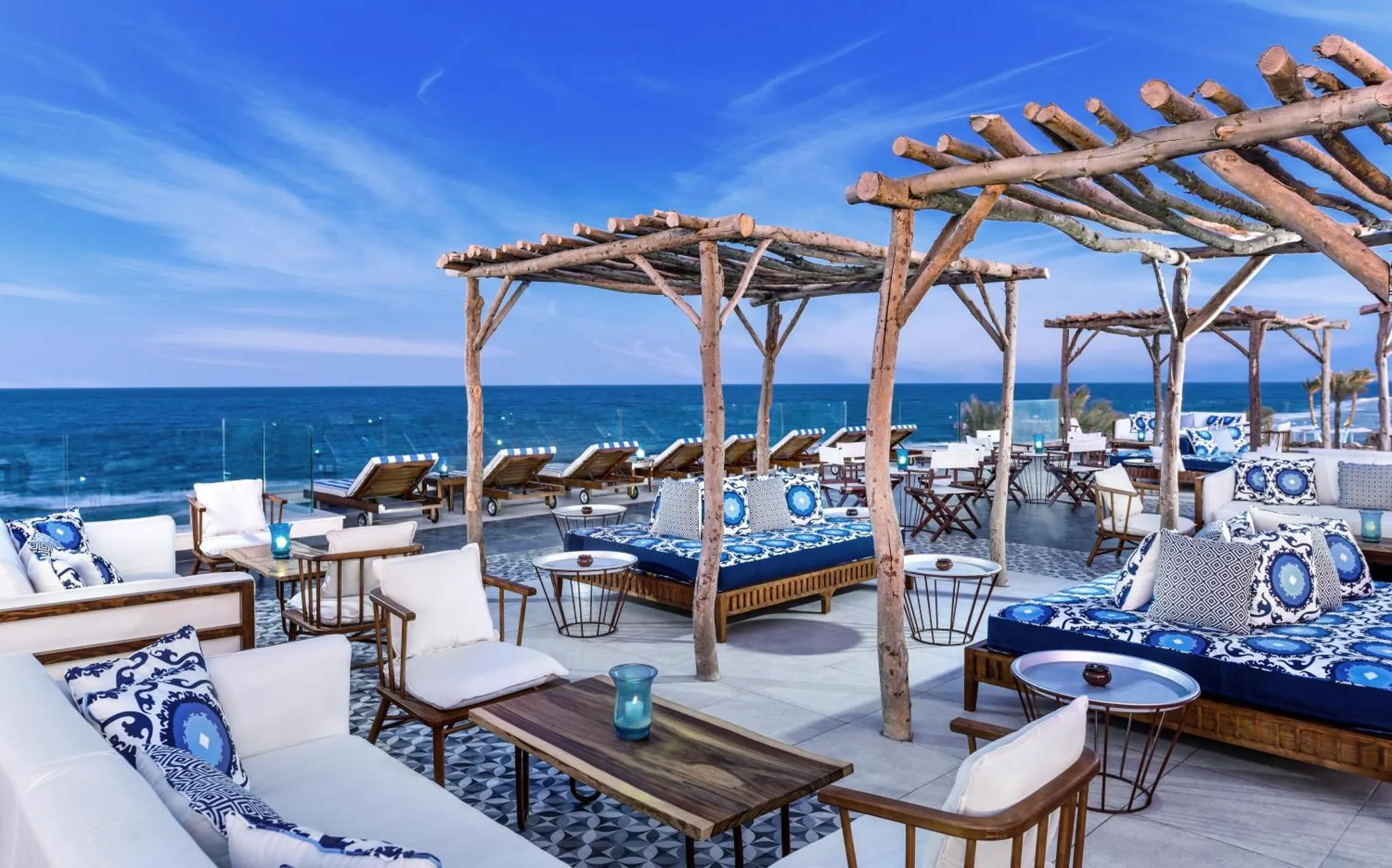 Terrasse aménagée avec des salons et des transats face à la mer.
